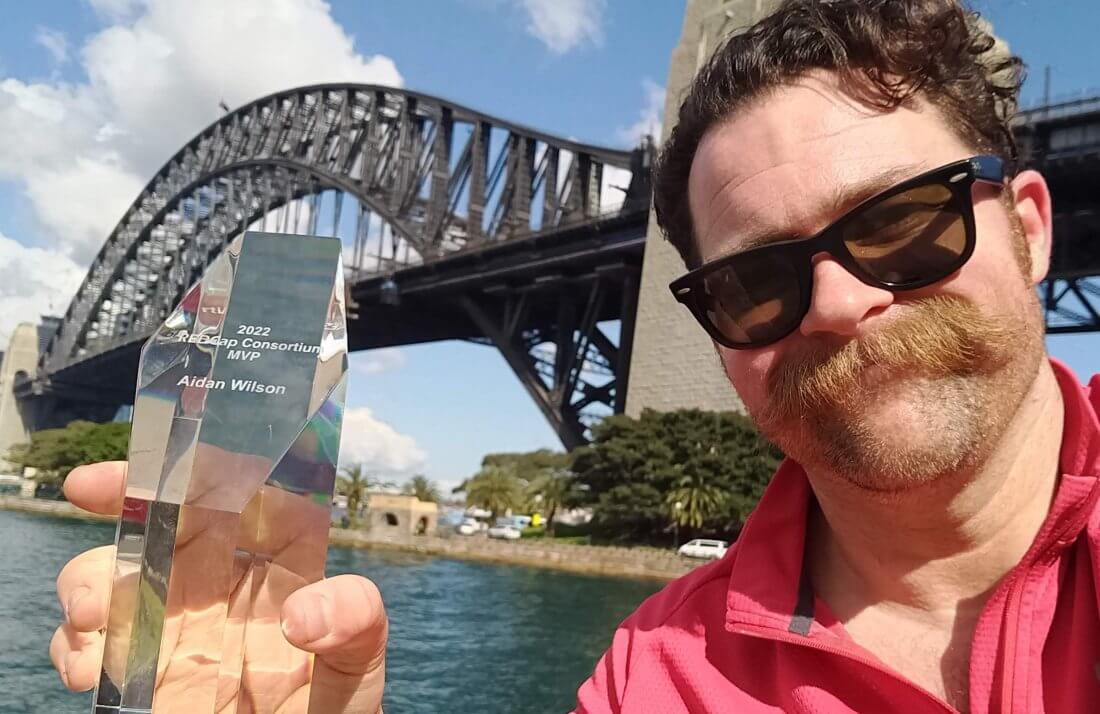 Aidan Wilson with REDCap Consortium MVP trophy and Sydney Harbour Bridge in background